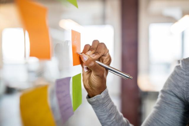 Female writing on sticky note